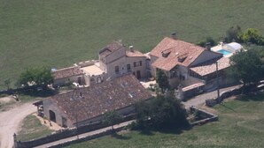 Vista aérea de una propiedad rural con una construcción grande, una piscina y follaje circundante.