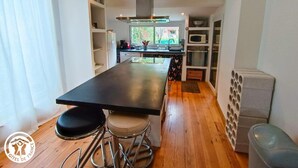 A compact kitchen with a central island, stools, a microwave, and a built-in oven. - Gîtes de France® - Le Fournil (GIGOUZAC)