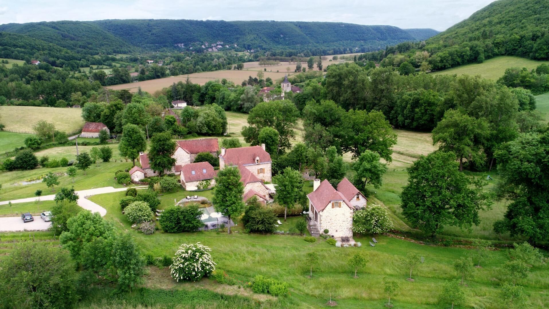 A rural village with stone houses, surrounded by lush greenery and hills.