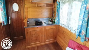 A compact kitchen with wooden cabinets, a built-in stove, and a sink. - Gîtes de France® - Roulotte de la Paille (LENDOU-EN-QUERCY)