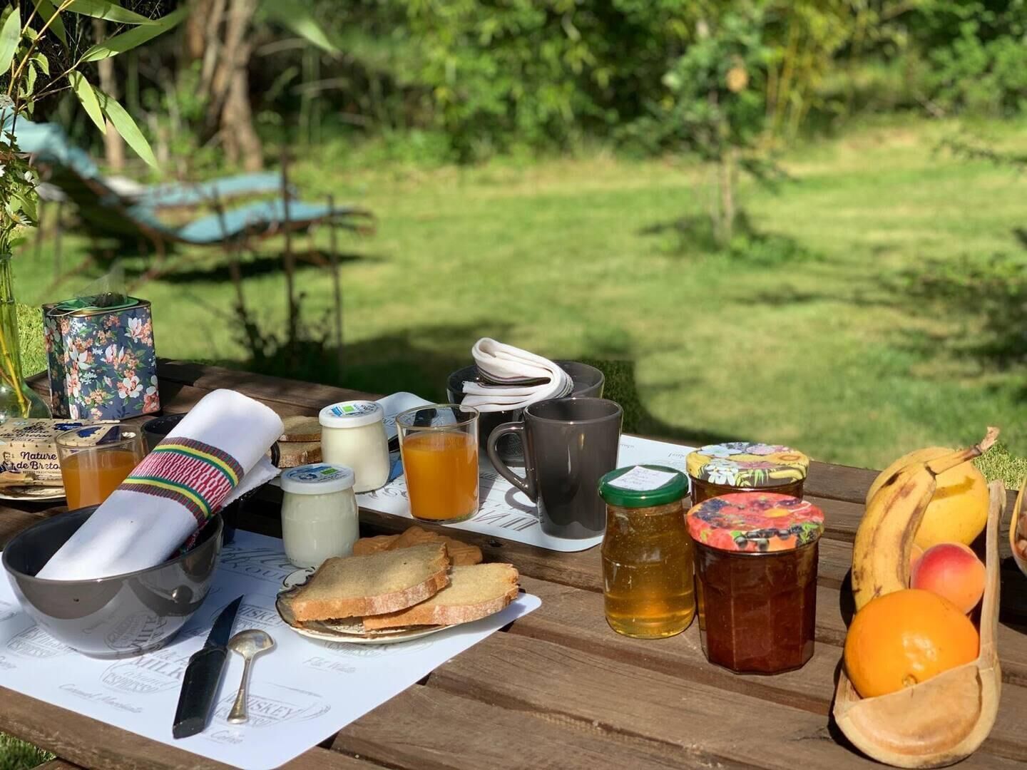Un montaje para picnic con comida, bebidas y un cuchillo sobre una mesa en un área con césped.