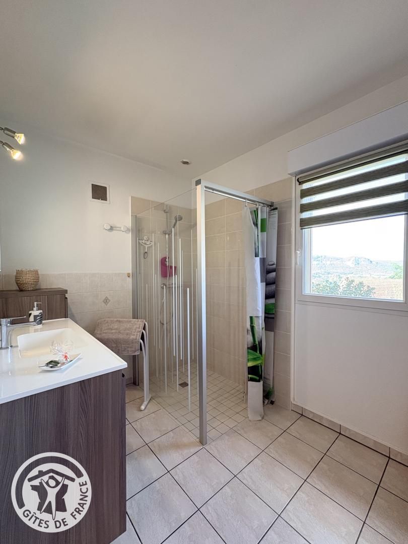 A modern bathroom with a shower, a sink, and a window.