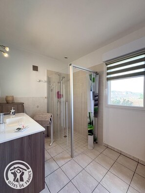Une salle de bain moderne avec une douche, un lavabo et une fenêtre.