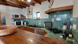 A kitchen with a wooden countertop, a microwave, a stove, and a sink. - Gîtes de France® - LES CIGALES (SAINT-SOZY)