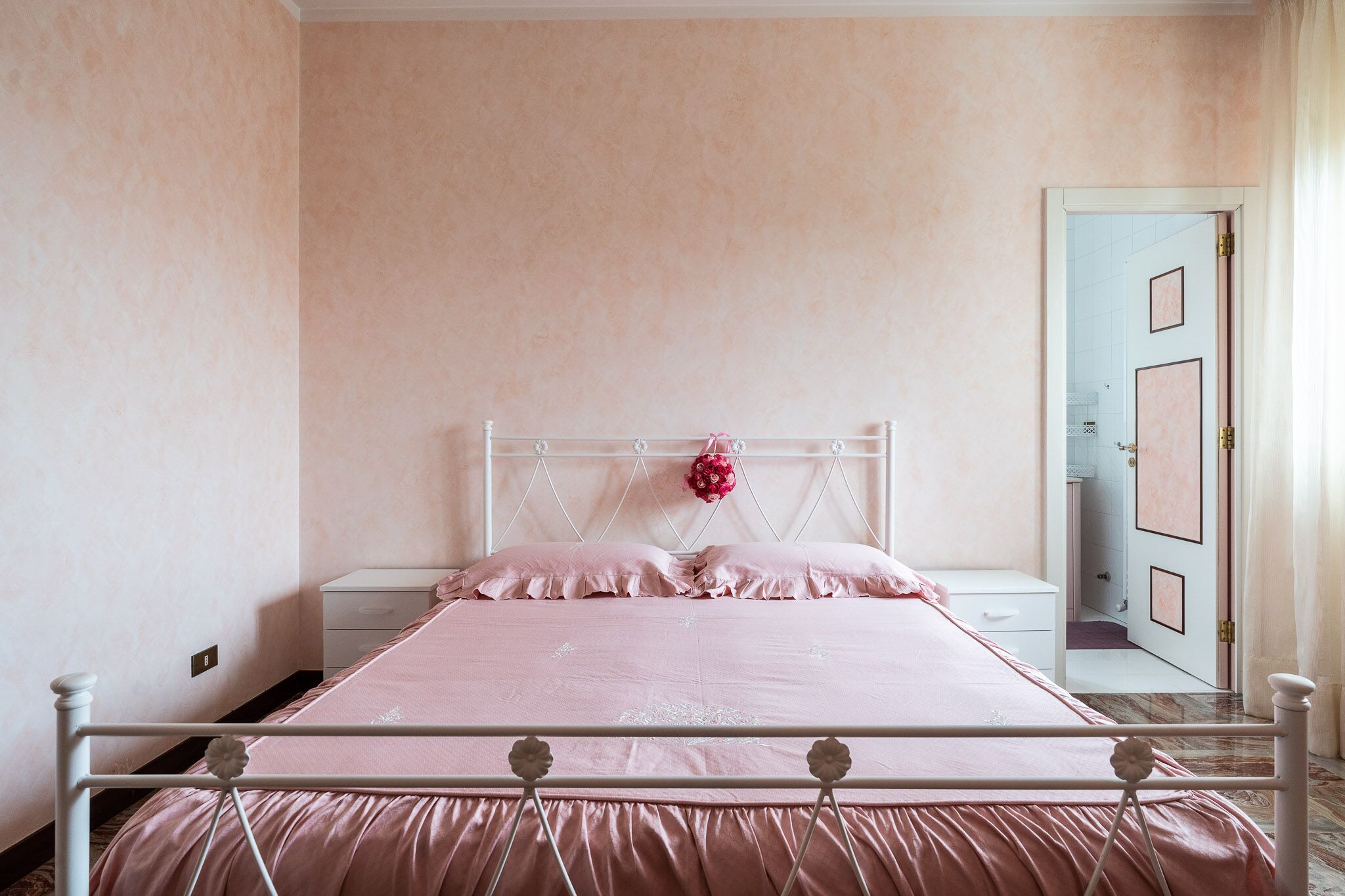 Un dormitorio con cama, mesita de noche y una puerta que da a otra habitación.