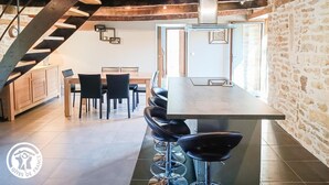 A modern kitchen with a central island, bar stools, and a staircase leading to an upper level.