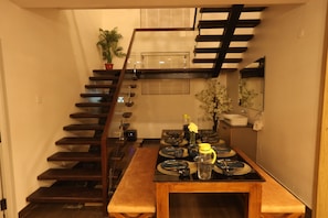 Una cocina moderna con una escalera de madera, una mesa de comedor con platos y una planta en maceta.