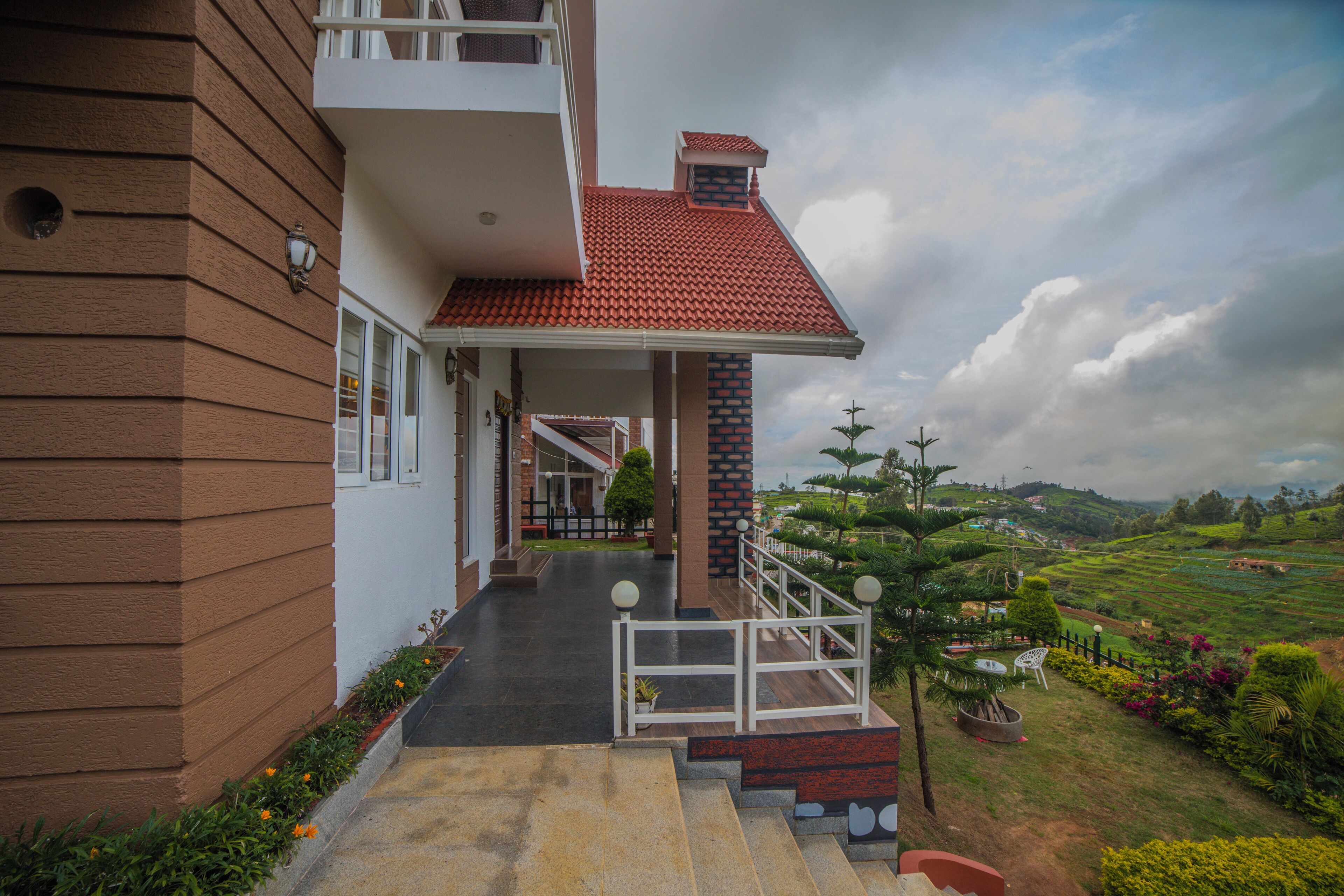 A two-story building with a red-tiled roof, a covered entrance, and a view of a landscaped garden.