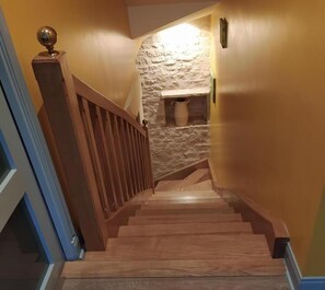 A wooden staircase with a stone wall and a small window.