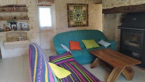 Uma sala de estar aconchegante com um sofá verde-água, almofadas coloridas listradas, uma mesa de centro de madeira e uma lareira.