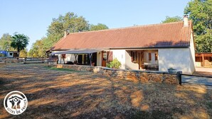 A rustic house with a stone foundation and a tiled roof, surrounded by a stone wall and a fenced yard. - Gîtes de France® - Le Gîte des Buis du Causse (SAINT SULPICE)