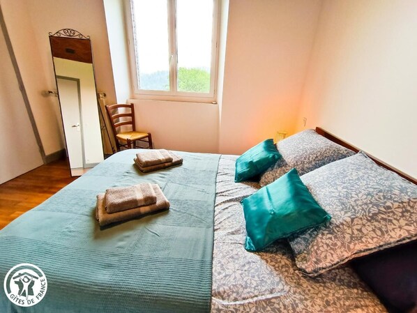 A bedroom with a bed, two pillows, a chair, and a window.
