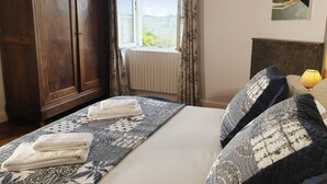 Un dormitorio con una cama grande, un armario, una ventana con cortinas y un cuadro en la pared.