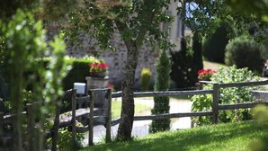 Un jardín con cerca de madera, muro de piedra y diversas plantas y flores.