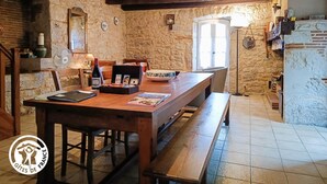 Un comedor rústico con una mesa de madera, bancos y paredes de piedra.