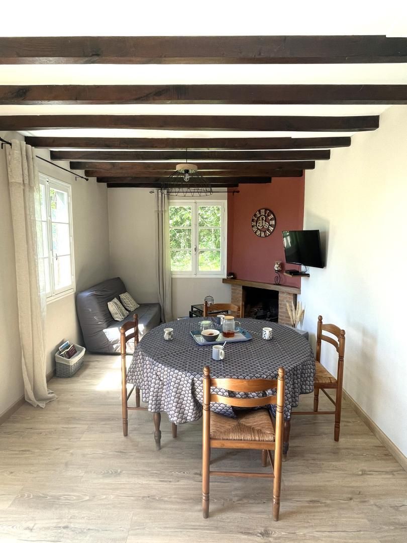 Ein Essbereich mit einem runden Tisch, Stühlen, einer Uhr und einem Fernseher an der Wand.
