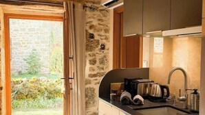 Cocina con paredes de piedra, vigas de madera y vistas a través de una puerta.