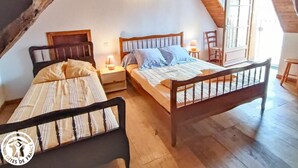 Quarto de sótão aconchegante com duas camas de madeira, teto inclinado e janela com vista.
