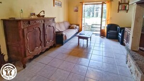 Uma sala de estar aconchegante com um sofá, um armário de madeira e uma mesa. Há uma janela com vista para o exterior.