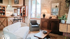 Ein gemütliches Wohnzimmer mit einer Couch, einem Korbsessel, einem Holztisch und einer Küchenzeile mit Holzausstattung.