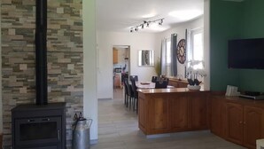 Una cocina amplia con una isla central, un muro de piedra y una estufa negra.