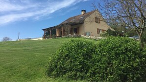 Una casa con techo inclinado, chimenea y cimientos de piedra.