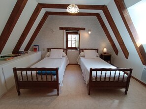Cozy attic bedroom with two single beds, nightstands, and a small window.