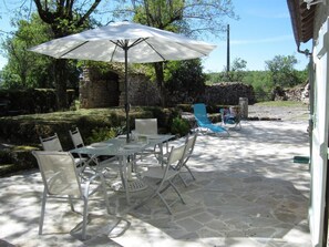Relax in a serene garden setting with a patio featuring a round table and comfortable seating.