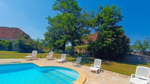 Una piscina con lettini bianchi e un patio in pietra.