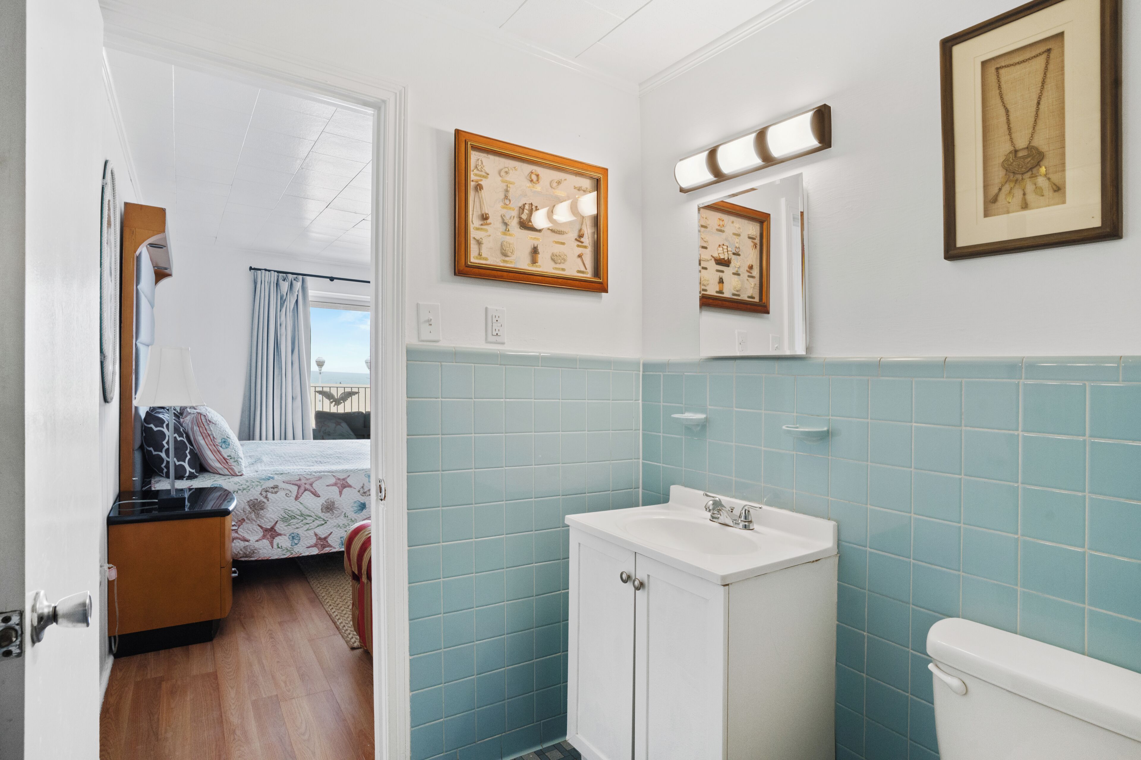 Een badkamer met wastafel, toilet en een bed met uitzicht uit het raam.