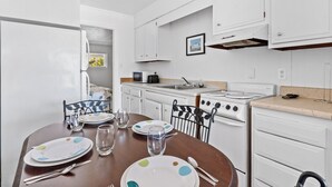 Une cuisine avec des meubles blancs, un fourneau et une table à manger dressée avec des assiettes et des verres.