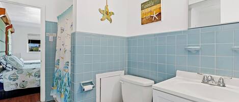 Een badkamer met toilet, wastafel en douchegordijn met een vispatroon.