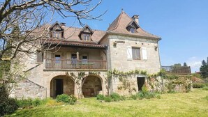 A stone building with a balcony and arched entrance.