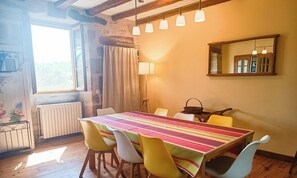 A dining area with a wooden table, colorful chairs, a mirror, and a window with curtains.