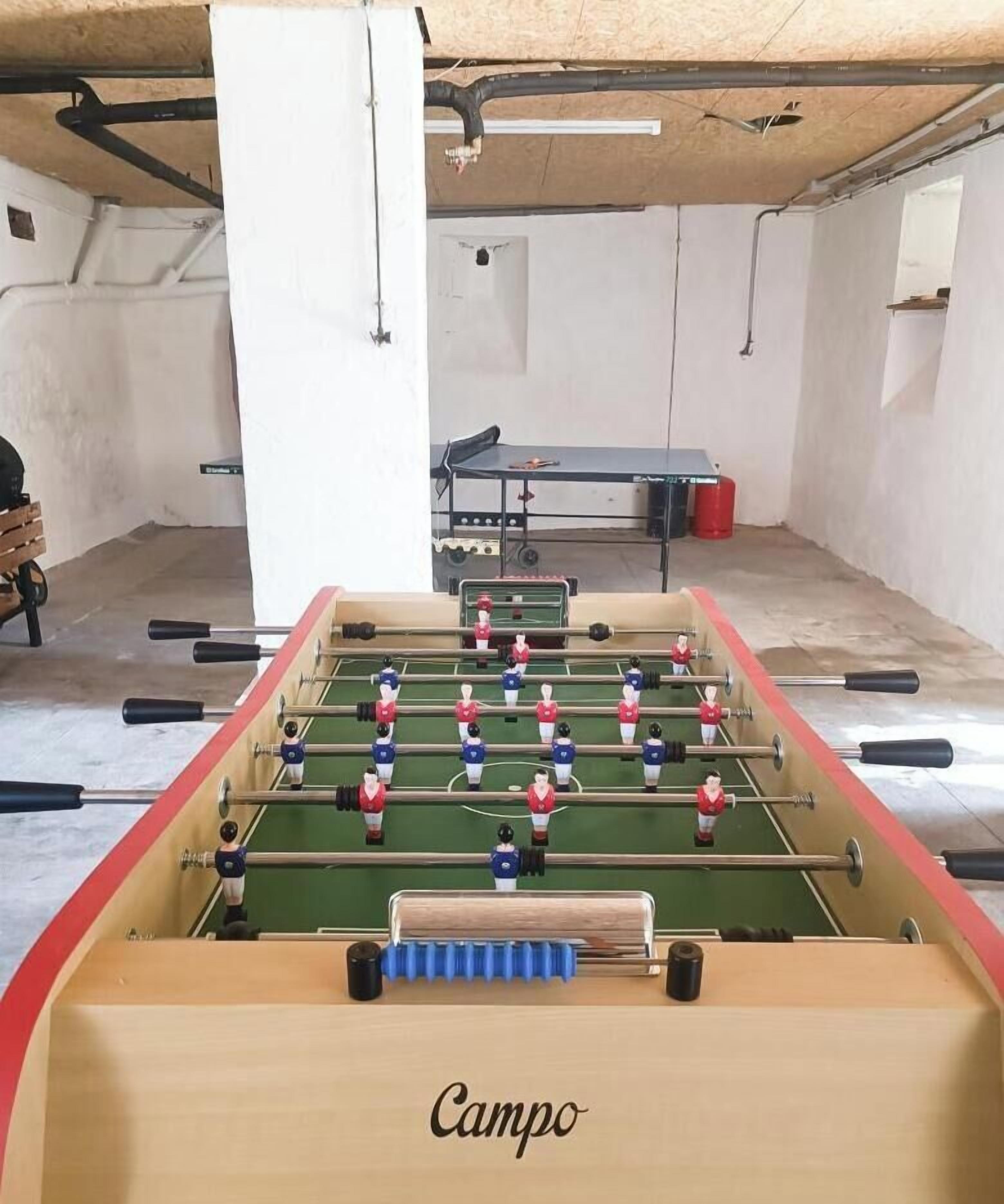 A foosball table with the brand 'Campo' in a room with a concrete floor and white walls.