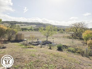 A rural landscape with a fenced area, a wooden structure, and a tree.