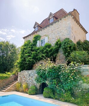 A stone building with a swimming pool, surrounded by greenery and a stone staircase. - Gîtes de France® - Le Moulin sur Célé (SAINT SULPICE)