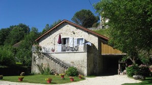 A stone building with a balcony, a staircase, and potted plants in the foreground. - Gîtes de France® - Gite de la Rivière Basse (MONTBRUN)