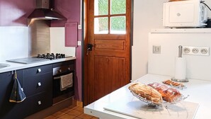 Cozinha com fogão, forno e vitrine de pão.