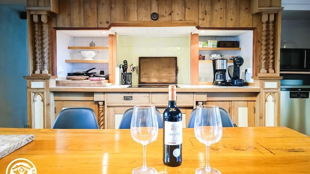 Una mesa de madera para comer con dos copas de vino y una botella.