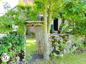 Experience the charm of a traditional French building surrounded by lush greenery and a well-manicured garden.