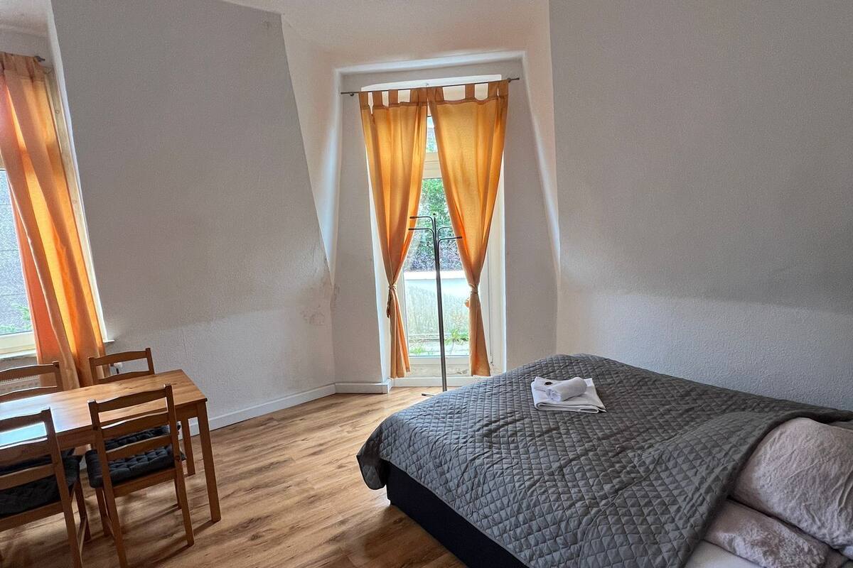 A bedroom with a bed, a wooden table, and chairs.