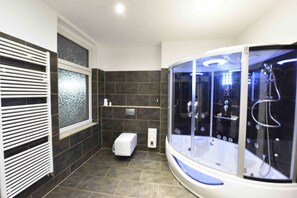 Un baño moderno con ducha envuelta en vidrio, inodoro y calefacción integrada.