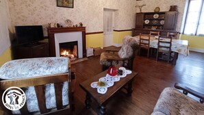 Un salon chaleureux avec une cheminée, des meubles en bois et un coin repas comprenant une table et des chaises.
