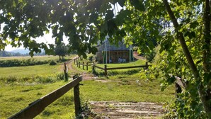 Un paysage rural avec un bâtiment en pierre, un chemin de terre et une clôture en bois.
