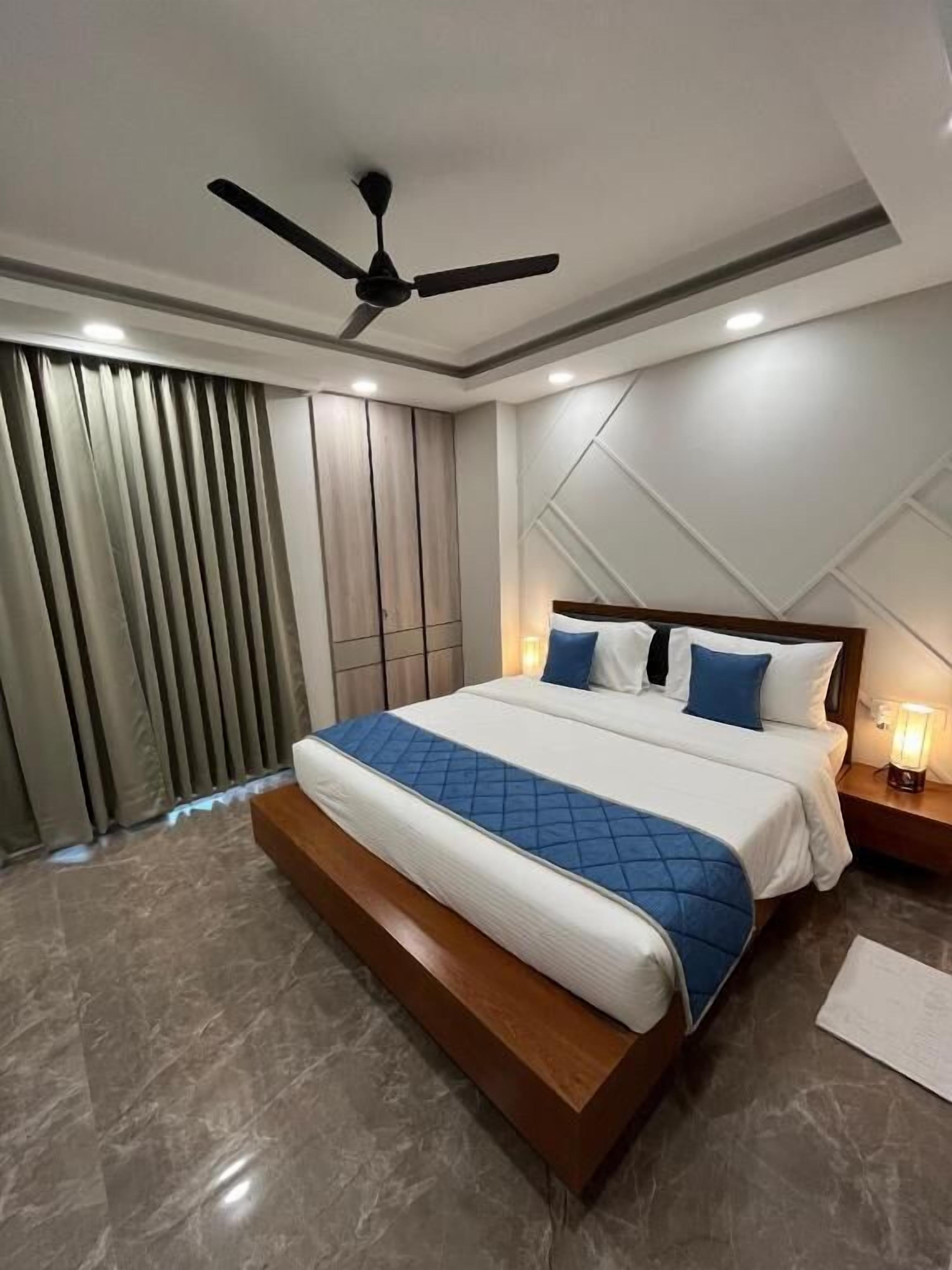 A modern hotel room with a large bed, a ceiling fan, and a nightstand with a lamp.