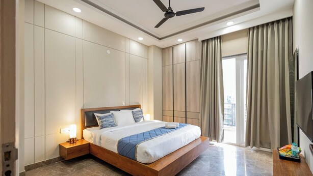 Una habitación de hotel moderna con una cama grande, un ventilador de techo, un televisor y vistas al exterior.