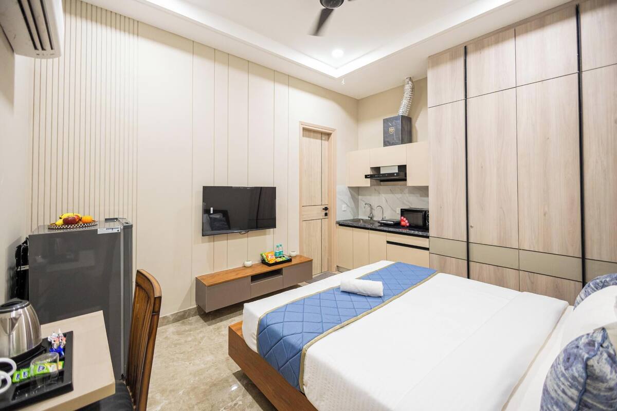 A hotel room with a bed, a TV, a kitchenette, and a wardrobe.