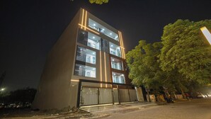 Un edificio moderno con varios pisos, ventanas amplias y una entrada protegida por un portón.