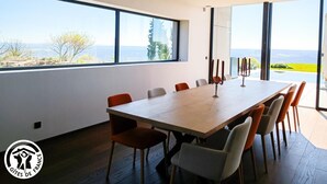 Een moderne eetruimte met een grote tafel en stoelen, grote ramen met uitzicht op het landschap.